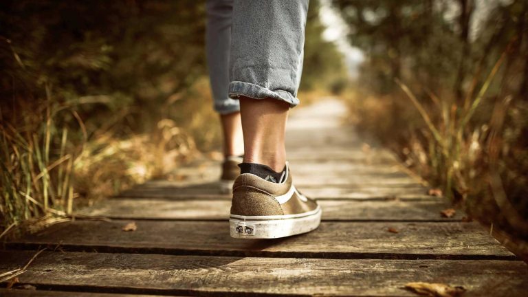 Nahaufnahme von 2 gehenden Füßen auf einem Holzsteg.