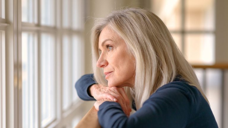 Ältere Frau schaut aus dem Fenster